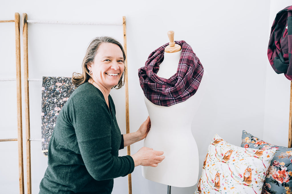 Amy pins a hidden pocket infinity scarf on a mannequin in her workroom