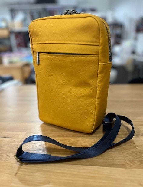 Mustard yellow sling bag with black strap front view