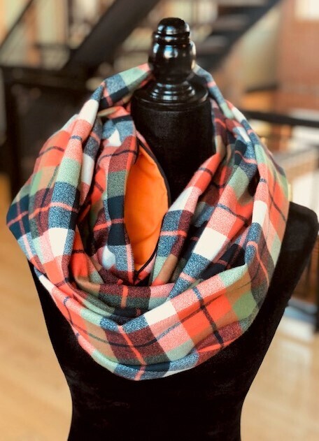 Hidden pocket infinity scarf with an orange, blue, green and cream plaid pattern