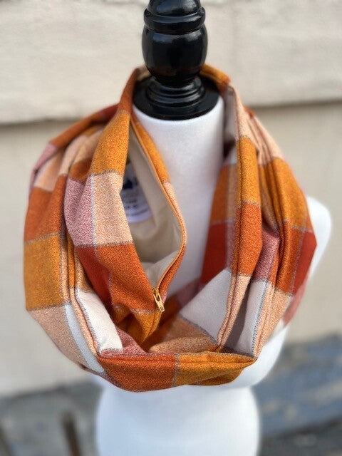 Hidden pocket infinity scarf with a light and dark orange large check pattern