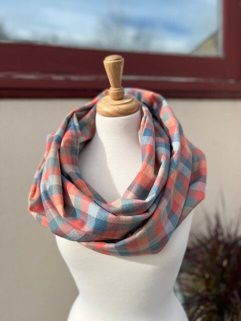 Hidden pocket infinity scarf with a blue, coral and pink plaid pattern
