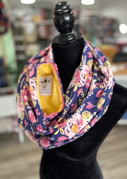 Hidden pocket infinity scarf with a floral print in yellows and pinks on a blue background