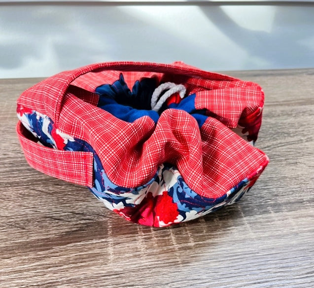 Red plaid cinch sac with blue and red floral accents